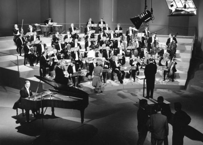 Dans le studio de télévision Ernst Becker de la Südwestfunk de Baden-Baden en 1964, l'orchestre symphonique de la Südwestfunk répète pour un enregistrement de Mozart avec le pianiste Rudolf Fircusny. Le chef d'orchestre est Ernest Bour. Une photo de Gerhard Heisler. Cliquer pour voir l'original du Bundesarchiv.